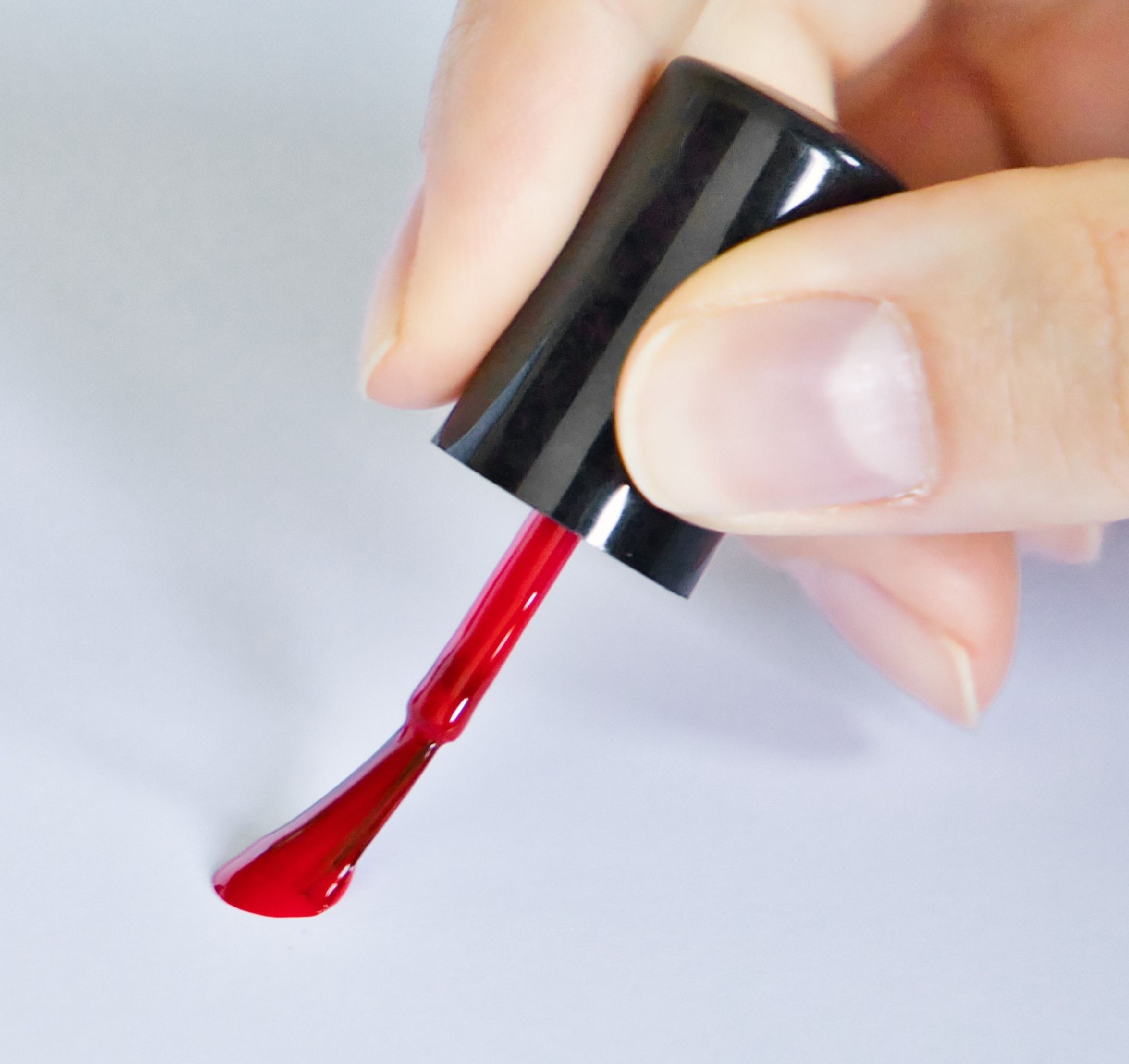 Das Bild zeigt wie ein roter Nagellack auf ein weißes Blatt aufgetragen wird.