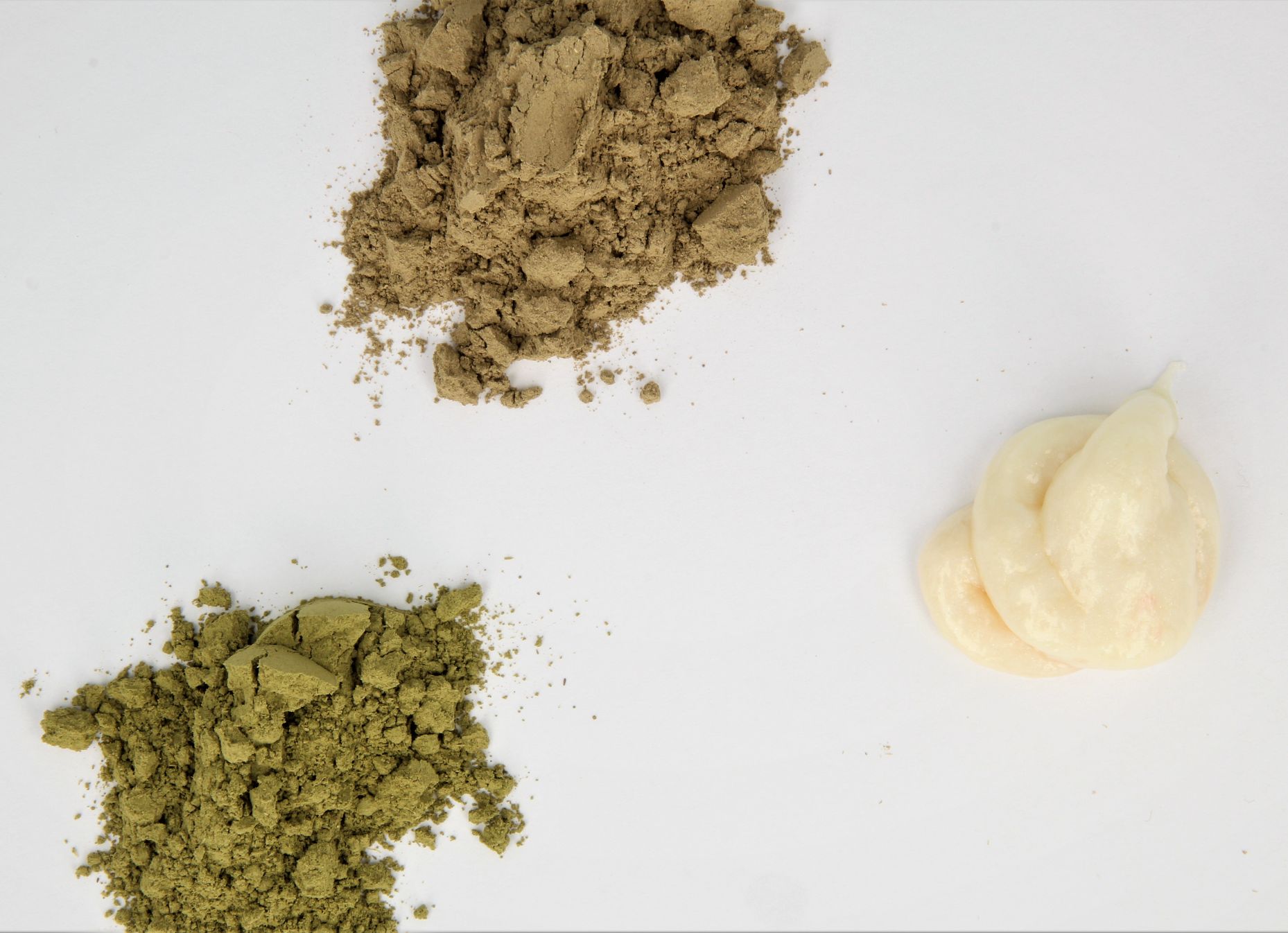 Das Bild zeigt zwei Hennapulver sowie einen Tupfen weißer Farbcreme.