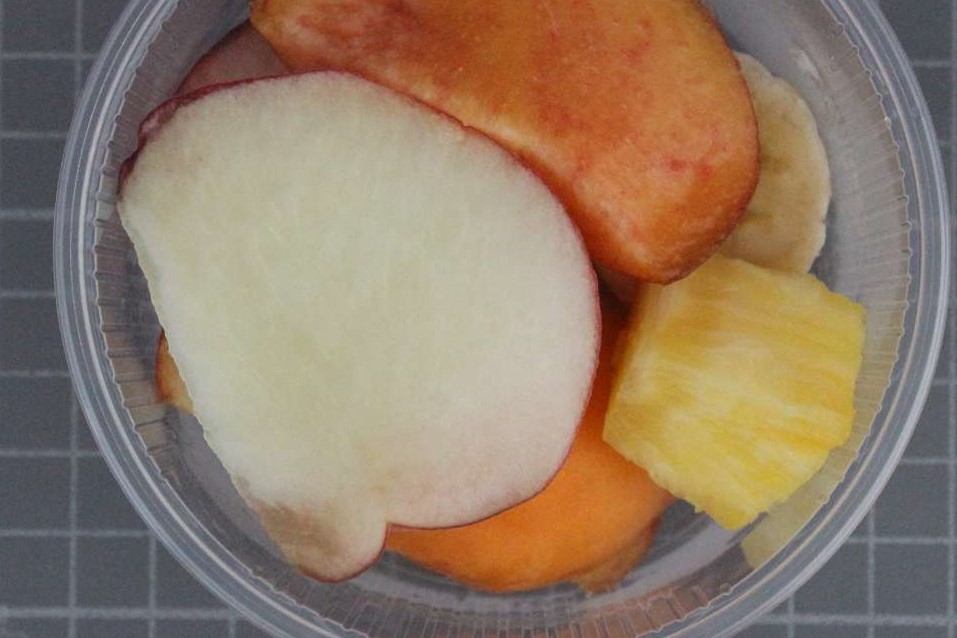Das Bild zeigt in einer Kunststoffdose Apfel-, Nektarinen-, Ananas- und Bananenstücke