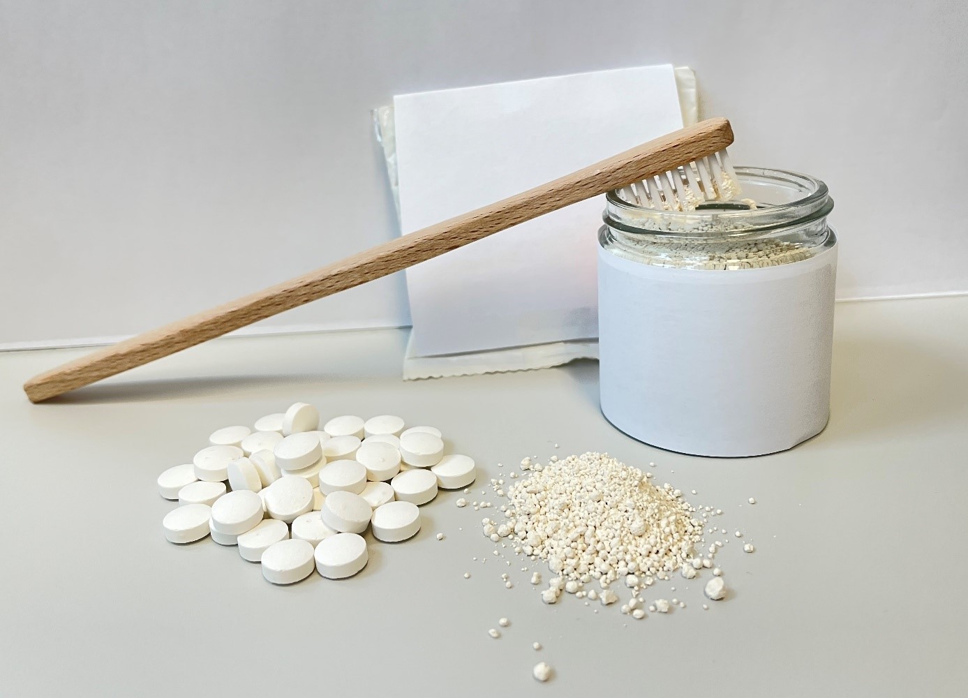 Das Foto zeigt eine Holzzahnbürste, Zahnputztabletten und Zahnputzpulver.