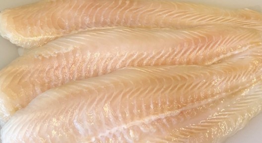 Die Abbildung zeigt drei Pangasius-Filets auf einem Schneidebrett.