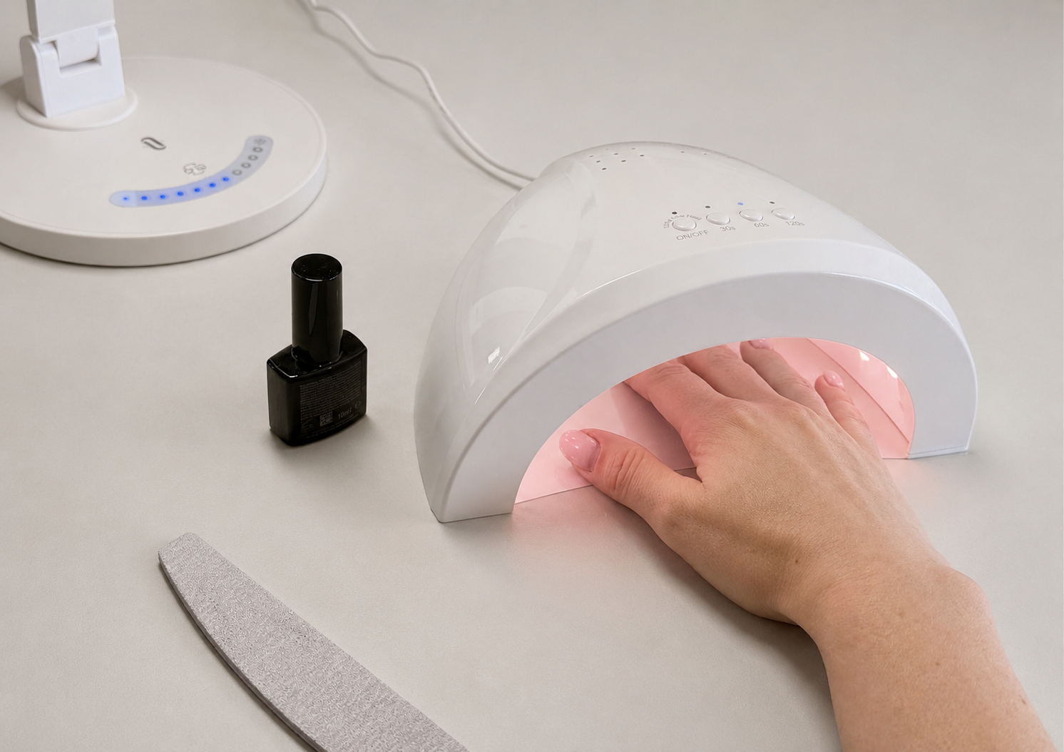 Das Bild zeigt eine Hand mit Nagellack, der unter einer Lampe aushärten.