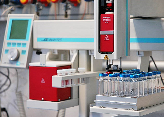 Das Bild zeigt einen Aufbau an dem Gaschromatographen mit einer Spritze zur Aufnahme der zu messenden Probe und Probengefe.